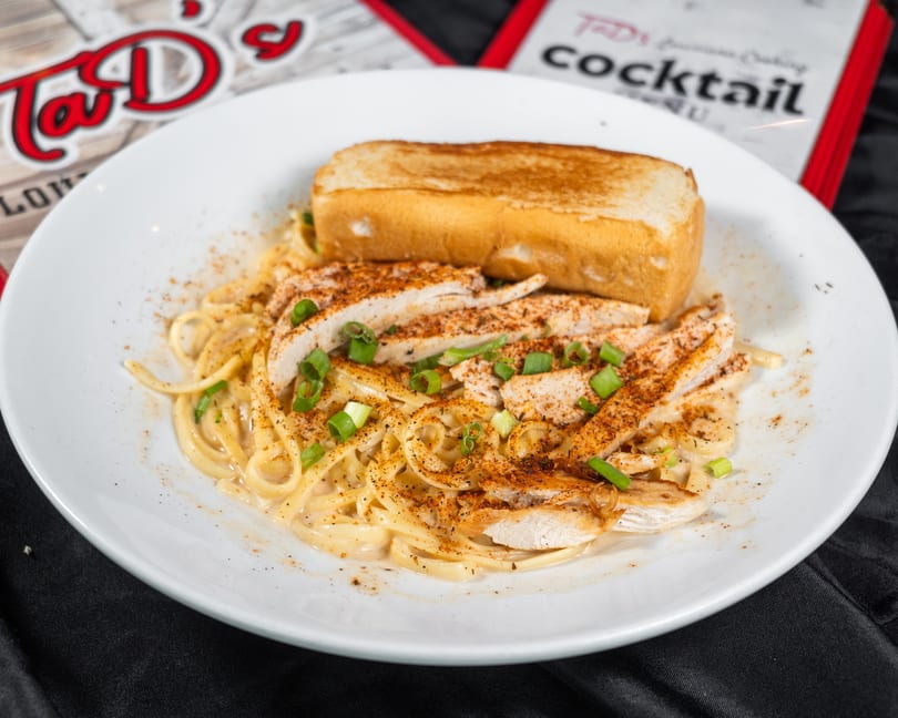 Tad's Louisiana Cooking chicken pasta with toasted bread, green onions, and seasoning.